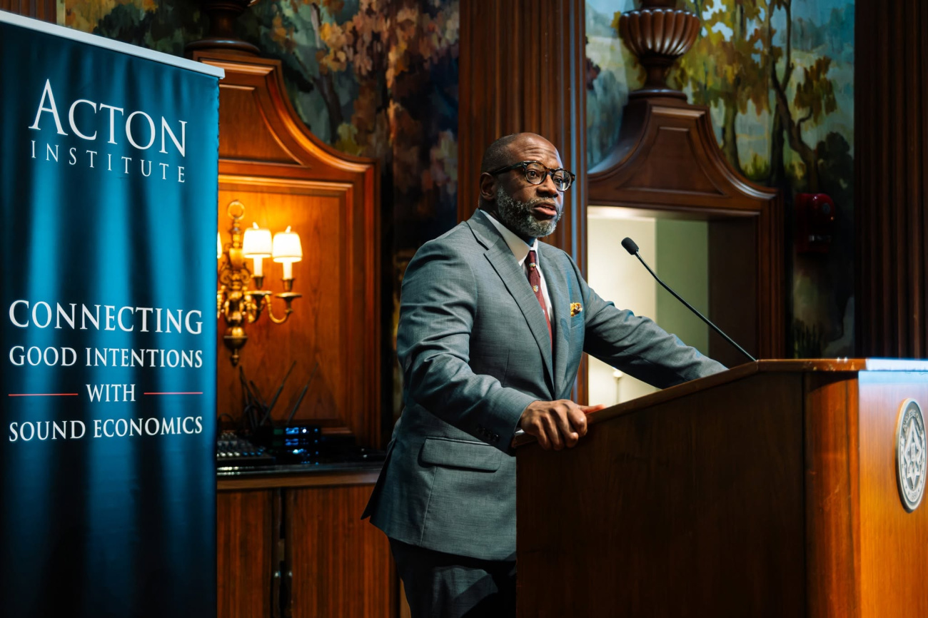 Anthony Bradley speaks at a lectern on stage in a historical, ornamental wood building